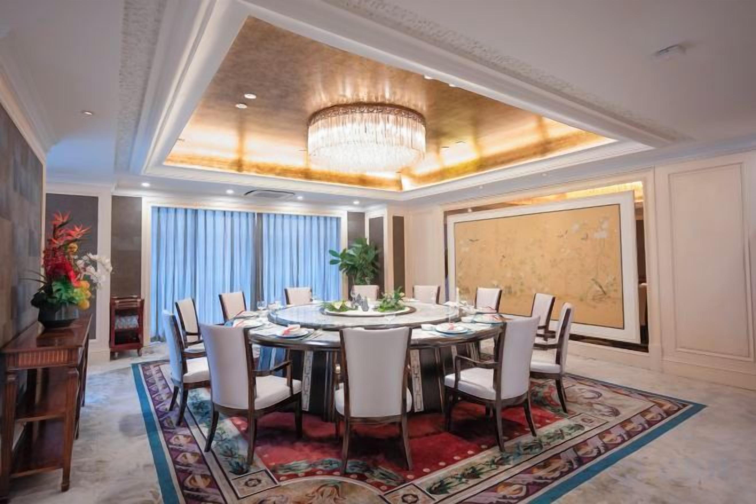 Ein formeller Speisesaal mit einem runden Tisch, Stühlen und einer Chandelier.
