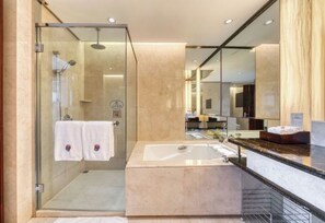 Un baño moderno con ducha de vidrio, un espejo grande y un lavamanos de mármol.