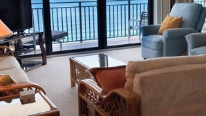 Una stanza con un'ampia finestra vista mare, una televisione e un'area salotto con tavolo e sedie.