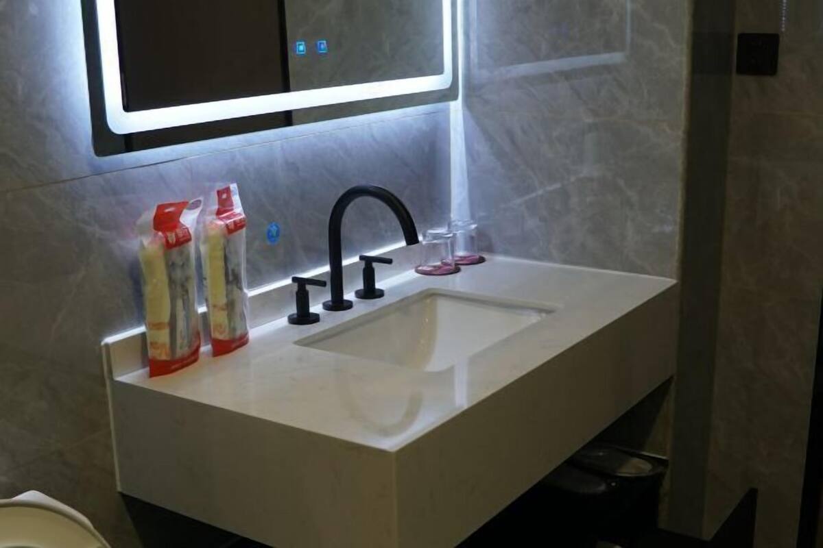 A modern bathroom with a white sink, black faucet, and a mirror above it.