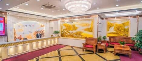 A hotel lobby with a reception desk, seating area, and artwork on the walls.