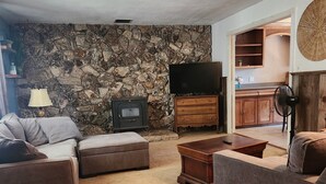 A living room with a stone wall, a television, and a wooden cabinet.
