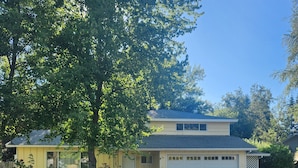 A two-story house with a garage, surrounded by trees and a driveway.