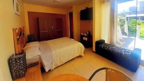 A hotel room with a bed, a small table, a chair, a TV, and a balcony with a view.