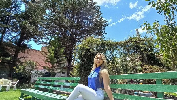 A person sitting on a green park bench.