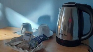 A table with a coffee maker, cups, and a tray with a packet of coffee and a packet of tea. - Los Jazmine's Eco Rooms (Chilca)
