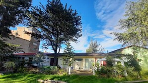 A residential property with a well-maintained lawn, a large tree, and a building with a tiled roof.