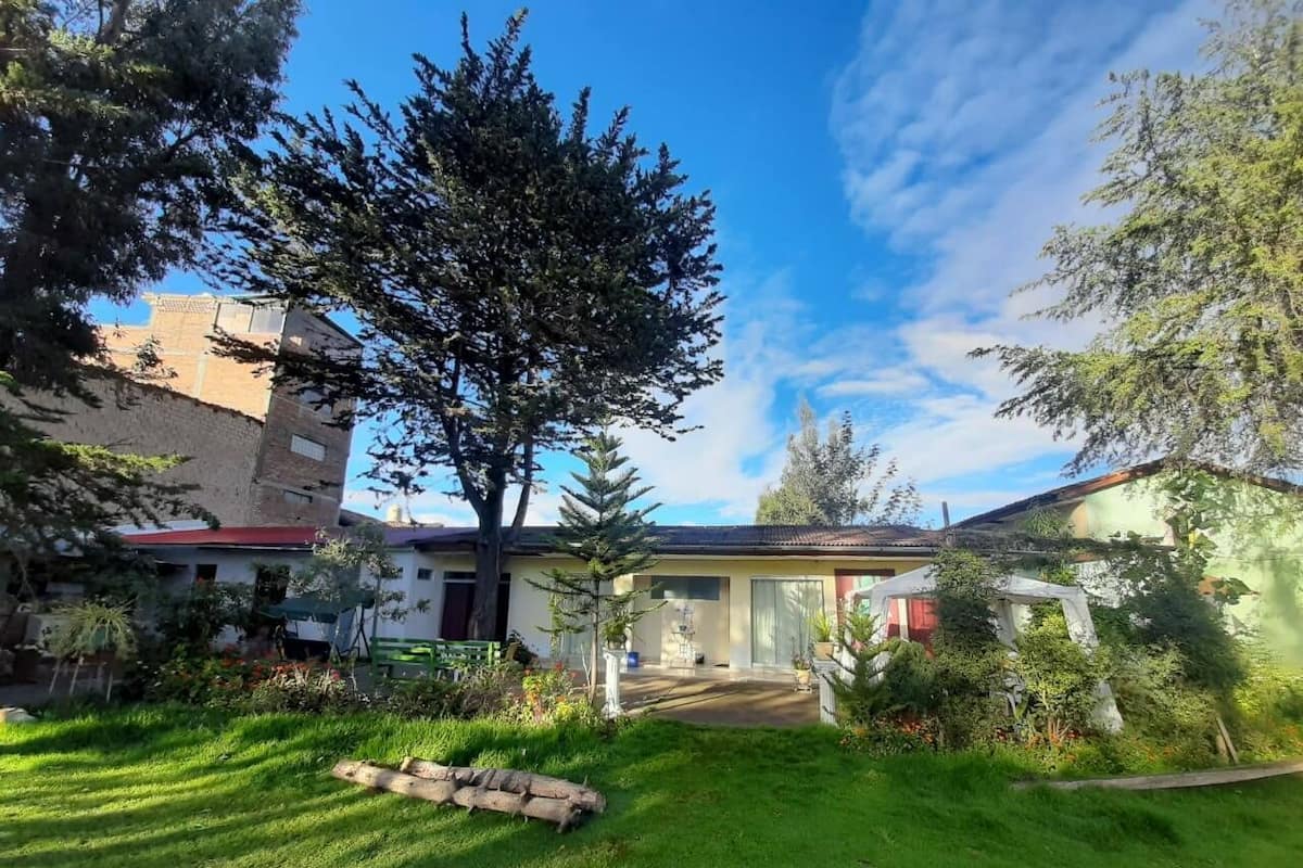 A residential property with a well-maintained lawn, a large tree, and a building with a tiled roof.