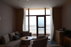 Et moderne hotelværelse med balkon, sofa, lille bord og stol.