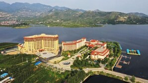 A large hotel with multiple buildings, a marina, and a lake surrounded by mountains.