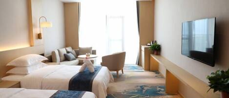 Une chambre d’hôtel avec deux lits, une télévision, un coin salon et une grande fenêtre.