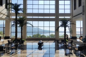 Un amplio espacio interior con grandes ventanales, un suelo reflectante y varias sillas dispuestas en el área.