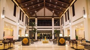 A spacious lobby with a high ceiling, large windows, and a central seating area.