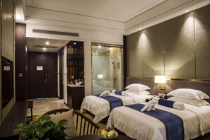 Een hotelkamer met twee bedden, een bureau, een stoel, een klein tafeltje met een fruitschaal en een grote spiegel.