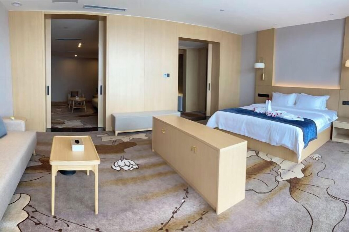 Et hotelværelse med seng, skrivebord, sofa og garderobeskab.