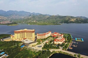 Un albergo con un edificio grande e una struttura più piccola, entrambi vicino all'acqua, con montagne sullo sfondo.