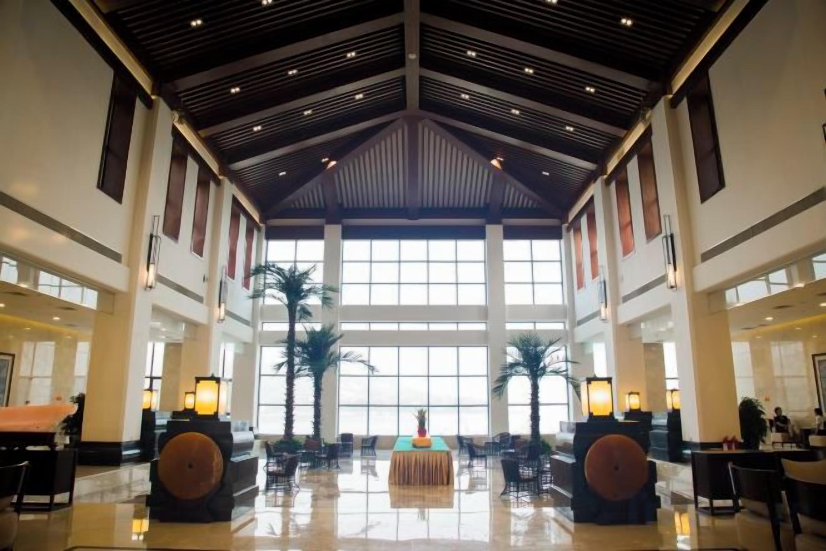 A spacious lobby with high ceilings, large windows, and a central seating area.