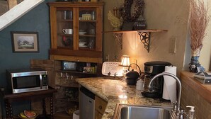 Une cuisine compacte dotée d’un évier intégré, d’un four à micro-ondes, d’un lave-vaisselle et d’un petit plan de travail.