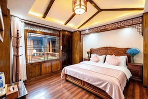 A traditional room with a wooden bed, a window with a view, and a decorative ceiling.