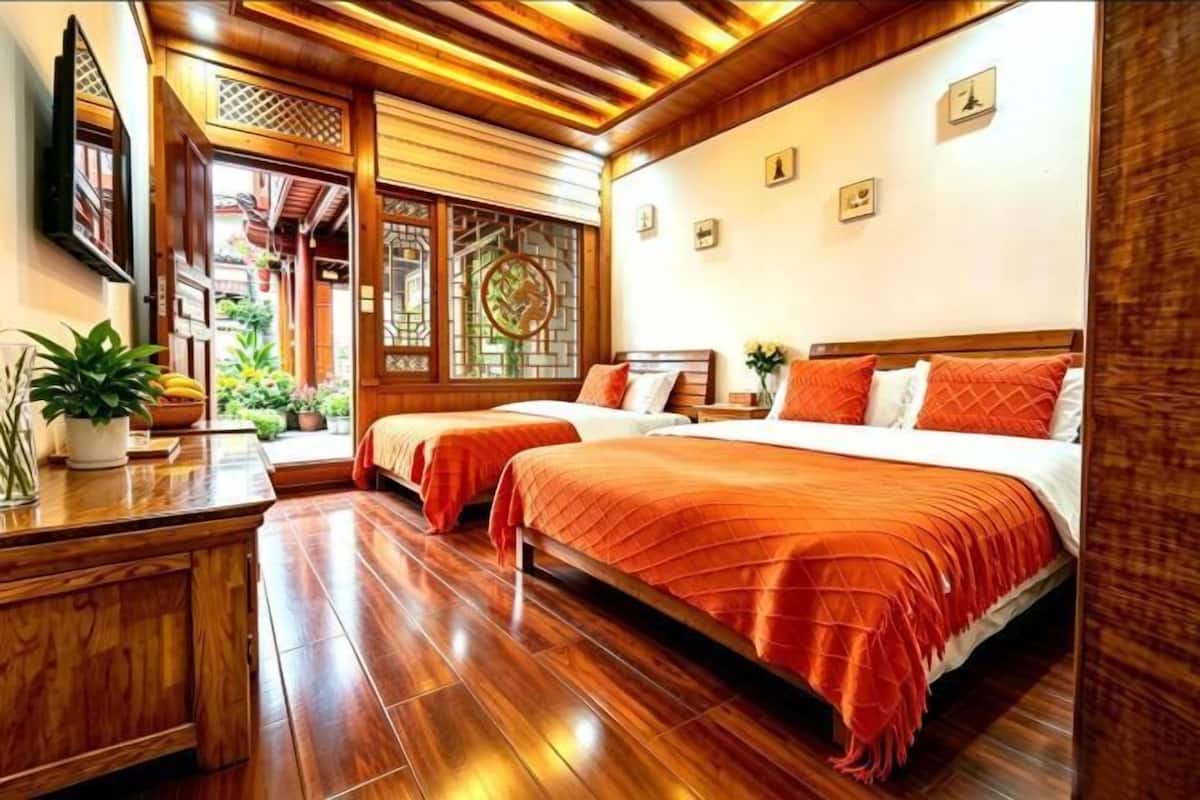 Una habitación con dos camas, suelo de madera, un escritorio con una planta y una puerta de madera tradicional.