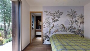 Ein Schlafzimmer mit einem großen Bett, einer Wandmalerei von tropischen Pflanzen und Holzboden.