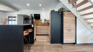Eine moderne Küche mit Holzboden, einem eingebauten Ofen und einem schwarzen Kühlschrank.
