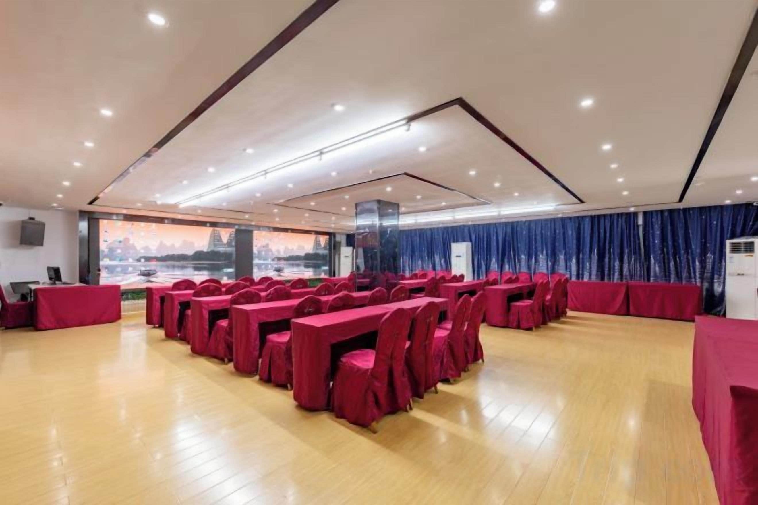 A conference room with tables and chairs, a large window with a view, and a blue curtain.