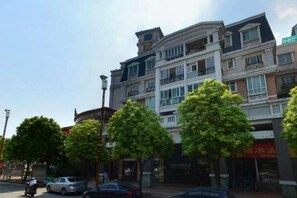 A multi-story building with balconies, a clear sky, and trees along the street. - Dihao Hotel (Guangzhou Panyu Shiqiao Aoyuan Plaza) (Guangzhou)