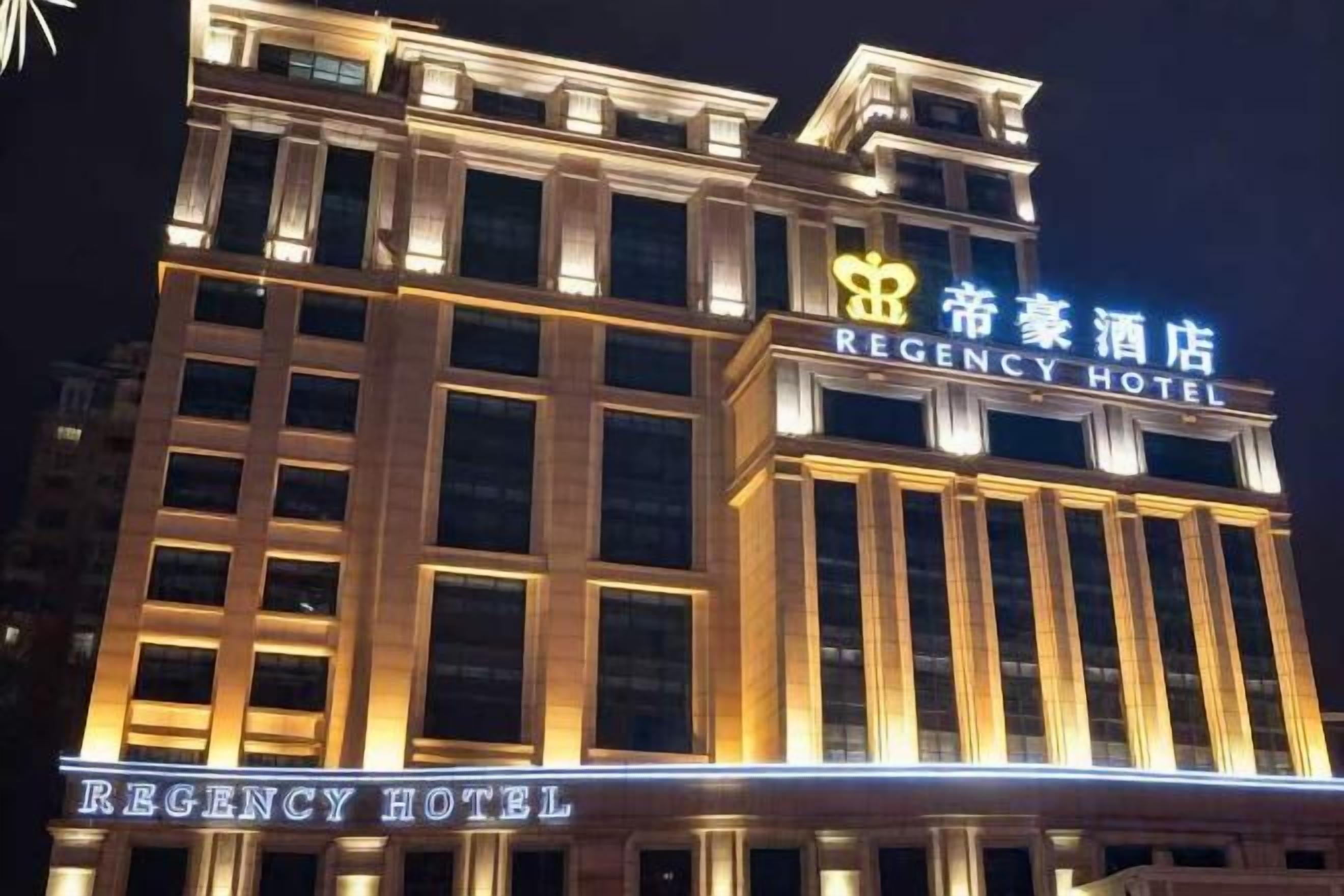 Um edifício de hotel com sinalização iluminada que exibe 'REGENCY HOTEL' e '帝豪酒店' em inglês e chinês.