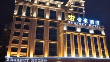Um edifício de hotel com sinalização iluminada que exibe 'REGENCY HOTEL' e '帝豪酒店' em inglês e chinês.