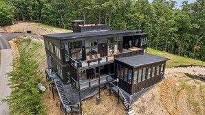 Une maison moderne à plusieurs étages, dotée de grandes fenêtres, d’un balcon et d’une terrasse.