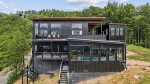 Une maison moderne à deux étages, dotée de grandes fenêtres, d’un balcon et d’une piscine.