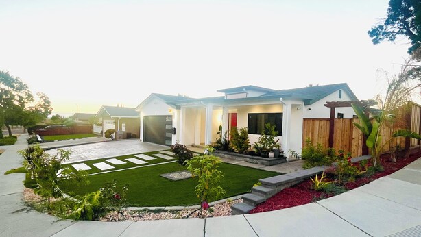 Une maison moderne à deux étages, dotée d’une pelouse bien entretenue, d’un patio couvert et d’une clôture en bois.