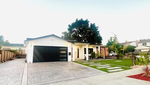 Une maison d’habitation avec un garage, une allée pavée et une pelouse bien entretenue.
