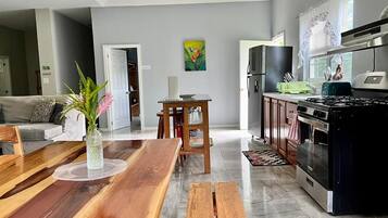 A modern kitchen with a stove, oven, and dining area with a wooden table and benches.