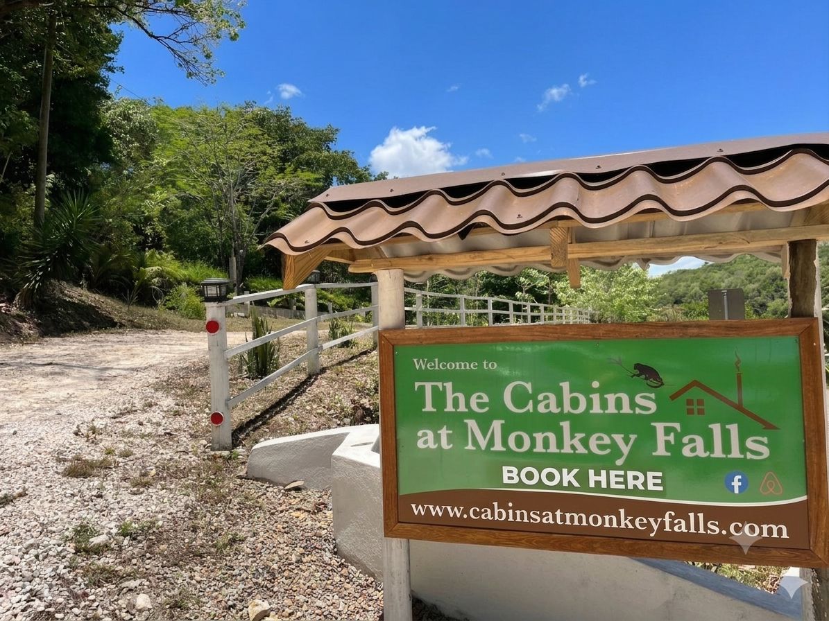 A welcome sign for The Cabins at Monkey Falls with a website URL and a Facebook icon.