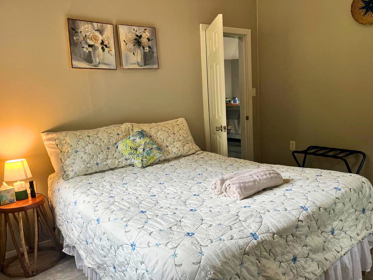 A bedroom with a bed, a nightstand, a lamp, and two paintings on the wall.