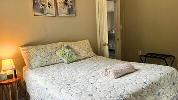 A bedroom with a bed, a nightstand, a lamp, and two paintings on the wall.