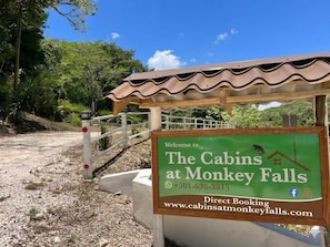 A welcome sign for The Cabins at Monkey Falls with a contact number and website for direct booking.