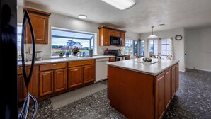 Una cocina con armarios de madera, una isla grande, un microondas y vistas al exterior.
