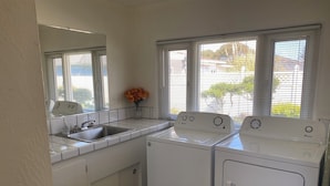 Zona de lavandería con un lavabo, dos lavadoras y un espejo.