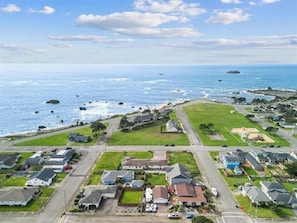 An aerial view of a coastal residential area with houses, roads, and a beach.