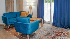 A living room with a blue sofa, a wooden coffee table, and a floor lamp. - Nice home in Neubrandenburg with WiFi (Neubrandenburg)
