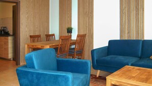 A living room with a blue sofa, a wooden coffee table, and a dining area with wooden chairs and a table. - Nice home in Neubrandenburg with WiFi (Neubrandenburg)