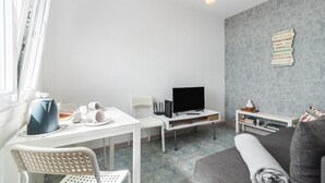 A modern living room with a white table, a grey sofa, and a TV. - Home2Book Stunning BeachFront Apt, Pozo Izquierdo (Pozo Izquierdo)