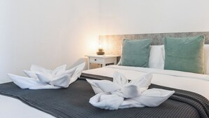 A hotel room with a neatly made bed, a nightstand with a lamp, and green pillows. - Home2Book Stunning BeachFront Apt, Pozo Izquierdo (Pozo Izquierdo)