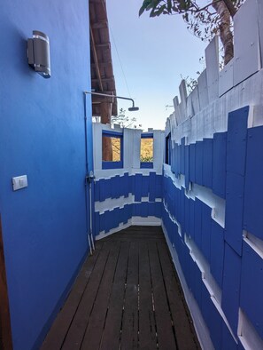 A narrow, blue-painted corridor with a wooden floor, leading to a small window.