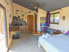 A compact, modern room with a kitchenette, a dining area, and a bed.