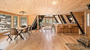 A wooden interior with a dining area, kitchen, and large windows. - A-Frame On The Rocks. Hot Tub. Payson. Waterwheel. (Payson)