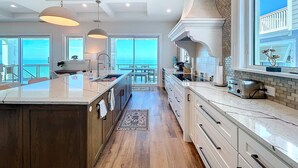 A spacious kitchen with a large island, modern appliances, and a view of the ocean.